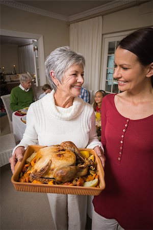 simsearch:400-07929054,k - Women posing with roast turkey in front of their family at home in the living room Stock Photo - Budget Royalty-Free & Subscription, Code: 400-07929033