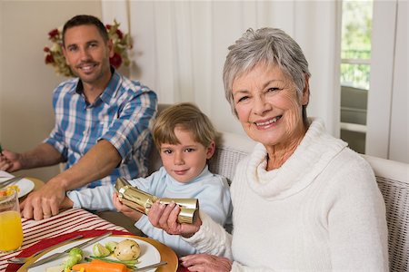 simsearch:400-07928326,k - Smiling family pulling christmas crackers at the dinner table at home in the living room Photographie de stock - Aubaine LD & Abonnement, Code: 400-07929050