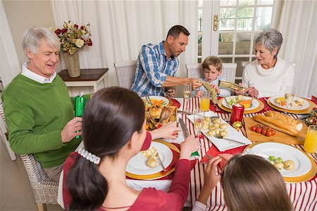 simsearch:400-07928326,k - Smiling family pulling christmas crackers at the dinner table at home in the living room Photographie de stock - Aubaine LD & Abonnement, Code: 400-07929051