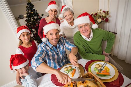 simsearch:400-07929054,k - Father in santa hat carving chicken at christmas dinner at home in the living room Stock Photo - Budget Royalty-Free & Subscription, Code: 400-07929067