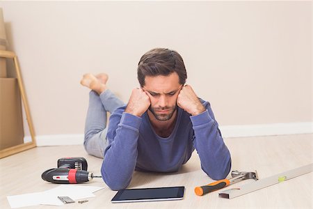 simsearch:400-07931092,k - Casual man lying on floor using tablet pc for DIY instructions at home in the living room Foto de stock - Super Valor sin royalties y Suscripción, Código: 400-07929293