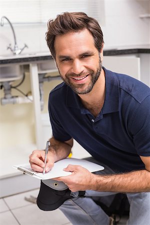 plumber kitchen sink - Plumber crouching and taking notes in the kitchen Stock Photo - Budget Royalty-Free & Subscription, Code: 400-07929377