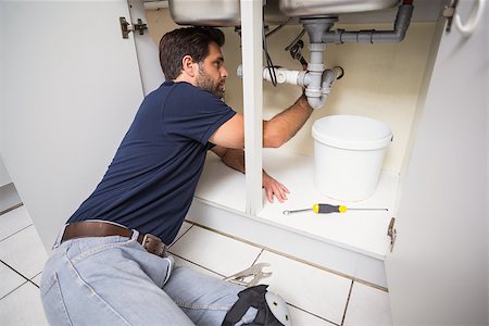 simsearch:400-07929795,k - Plumber fixing under the sink in the kitchen Stock Photo - Budget Royalty-Free & Subscription, Code: 400-07929379