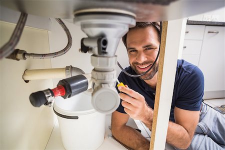 simsearch:400-07929795,k - Plumber fixing under the sink in the kitchen Stock Photo - Budget Royalty-Free & Subscription, Code: 400-07929384