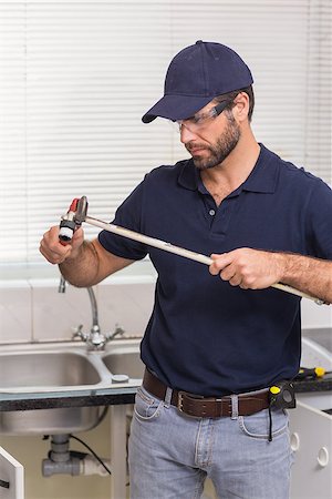 simsearch:400-07929361,k - Plumber fixing pipe with wrench in the kitchen Stockbilder - Microstock & Abonnement, Bildnummer: 400-07929398