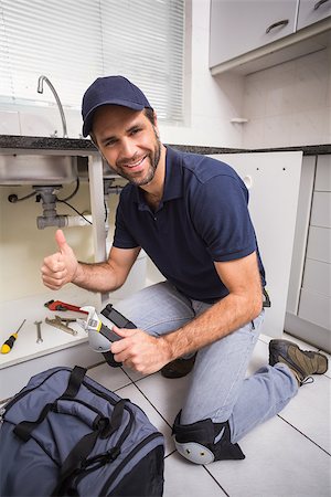 simsearch:400-07929795,k - Plumber fixing under the sink in the kitchen Stock Photo - Budget Royalty-Free & Subscription, Code: 400-07929390