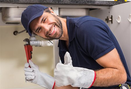 simsearch:400-07929795,k - Plumber smiling at the camera fixing under the sink in the kitchen Stock Photo - Budget Royalty-Free & Subscription, Code: 400-07929400