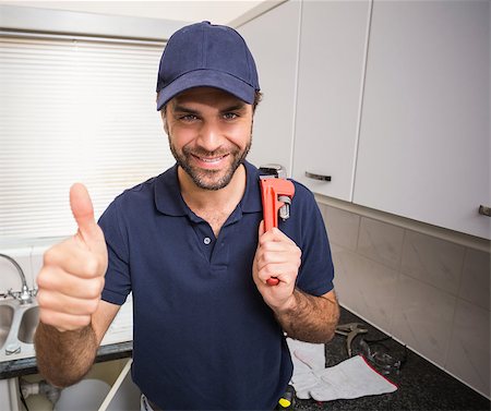 simsearch:400-07929795,k - Plumber smiling at the camera in the kitchen Stock Photo - Budget Royalty-Free & Subscription, Code: 400-07929401