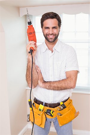 simsearch:400-07929840,k - Handyman smiling at camera holding drill in a new house Foto de stock - Super Valor sin royalties y Suscripción, Código: 400-07929555