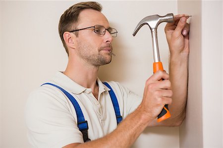 Handyman hammering nail in wall in a new house Stock Photo - Budget Royalty-Free & Subscription, Code: 400-07929745