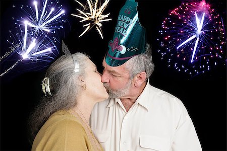 Beautiful senior couple at a New Year's party kisses at the stroke of midnight as the fireworks go off in the background. Stock Photo - Budget Royalty-Free & Subscription, Code: 400-07920881