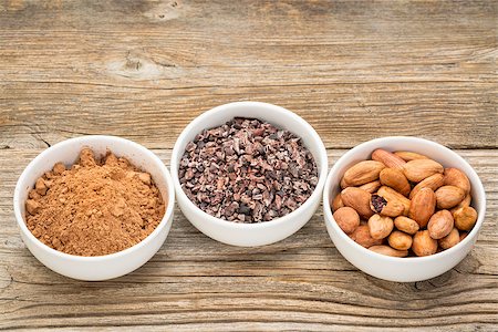 ponta de caneta - cacao beans, nibs and powder in white ceramic bowls against grained wood Foto de stock - Royalty-Free Super Valor e Assinatura, Número: 400-07922285