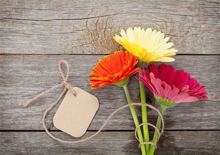 simsearch:400-07662543,k - Three colorful gerbera flowers with tag on wooden table Stock Photo - Budget Royalty-Free & Subscription, Code: 400-07922754