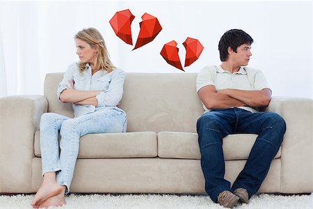 simsearch:400-06687238,k - A couple sit at the two ends of the couch with their arms folded looking away against broken hearts Fotografie stock - Microstock e Abbonamento, Codice: 400-07934769