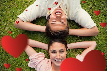 Two friends smiling while lying head to head with both hands behind their neck  against hearts Stock Photo - Budget Royalty-Free & Subscription, Code: 400-07934770