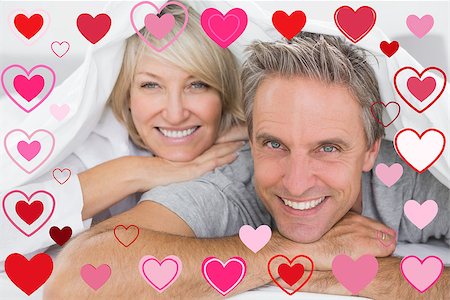 simsearch:400-06891126,k - Couple smiling under the covers against valentines heart design Stock Photo - Budget Royalty-Free & Subscription, Code: 400-07934780