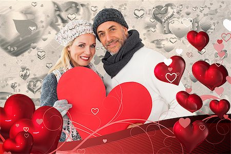 simsearch:400-07957430,k - Smiling couple in winter fashion posing with heart shape against grey valentines heart pattern Photographie de stock - Aubaine LD & Abonnement, Code: 400-07935009