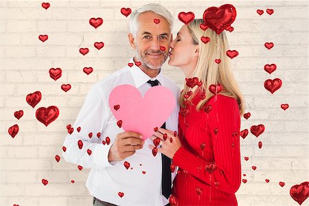 simsearch:400-07957627,k - Handsome man holding paper heart getting a kiss from wife against white wall Foto de stock - Super Valor sin royalties y Suscripción, Código: 400-07935055