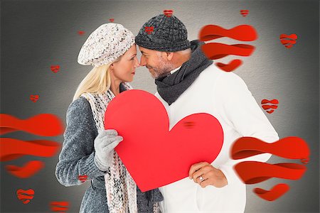 simsearch:400-07957430,k - Smiling couple in winter fashion posing with heart shape against white background with vignette Photographie de stock - Aubaine LD & Abonnement, Code: 400-07935064