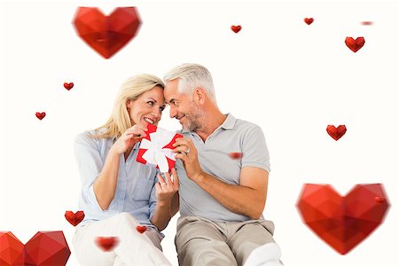 simsearch:400-07726694,k - Happy couple sitting and holding present against hearts Foto de stock - Royalty-Free Super Valor e Assinatura, Número: 400-07935110