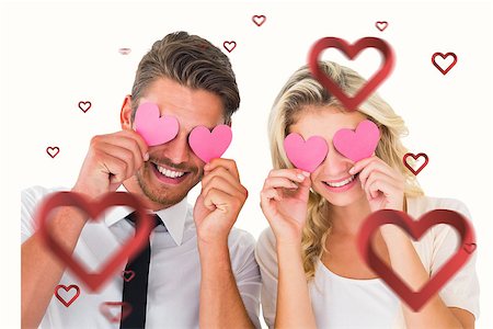 simsearch:400-06690931,k - Attractive young couple holding pink hearts over eyes against hearts Fotografie stock - Microstock e Abbonamento, Codice: 400-07935195