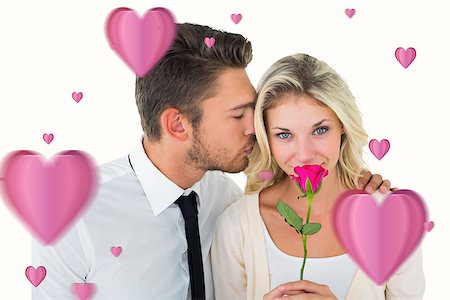 simsearch:400-07957805,k - Handsome man kissing girlfriend on cheek holding a rose against hearts Photographie de stock - Aubaine LD & Abonnement, Code: 400-07935202