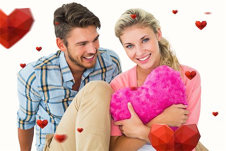 simsearch:400-07957805,k - Attractive young couple sitting holding heart cushion against hearts Photographie de stock - Aubaine LD & Abonnement, Code: 400-07935224
