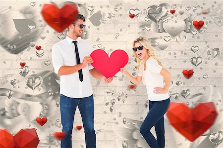 simsearch:400-07686534,k - Cool young couple holding red heart against grey valentines heart pattern Foto de stock - Royalty-Free Super Valor e Assinatura, Número: 400-07935264