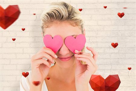 simsearch:400-06690931,k - Attractive young blonde holding hearts over eyes against white wall Fotografie stock - Microstock e Abbonamento, Codice: 400-07935265