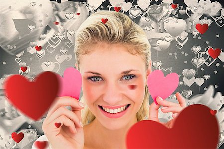 simsearch:400-07686534,k - Attractive young blonde holding little hearts  against grey valentines heart pattern Foto de stock - Royalty-Free Super Valor e Assinatura, Número: 400-07935262
