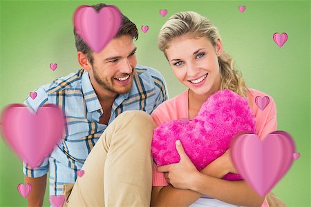 simsearch:400-07935196,k - Attractive young couple sitting holding heart cushion against green vignette Foto de stock - Royalty-Free Super Valor e Assinatura, Número: 400-07935284
