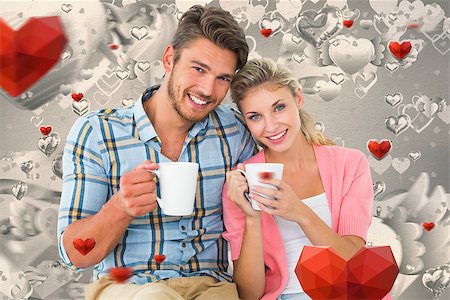 simsearch:400-07935196,k - Attractive young couple sitting holding mugs against grey valentines heart pattern Foto de stock - Royalty-Free Super Valor e Assinatura, Número: 400-07935286