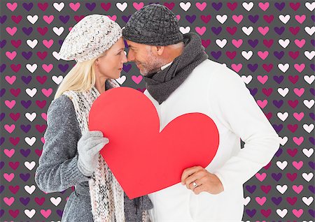simsearch:400-07957212,k - Smiling couple in winter fashion posing with heart shape against valentines day pattern Stock Photo - Budget Royalty-Free & Subscription, Code: 400-07935288
