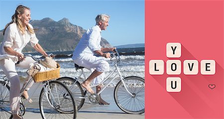 Smiling couple riding their bikes on the beach against love you tiles Stock Photo - Budget Royalty-Free & Subscription, Code: 400-07935586
