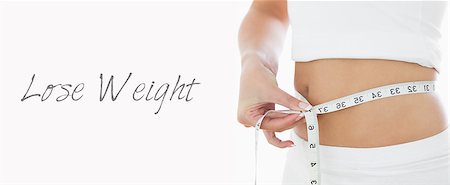 simsearch:614-06168638,k - Closeup midsection of woman measuring waist over white background Stockbilder - Microstock & Abonnement, Bildnummer: 400-07936548