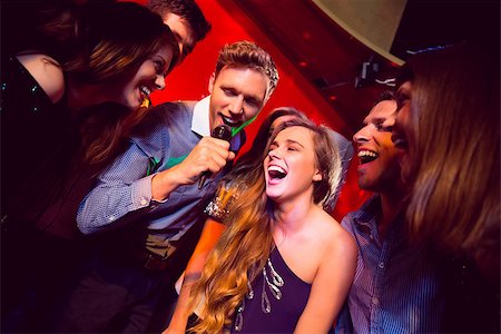 simsearch:400-07939979,k - Happy friends singing karaoke together at the nightclub Fotografie stock - Microstock e Abbonamento, Codice: 400-07938601