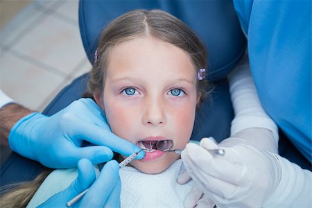 simsearch:6109-08389794,k - Dentist with assistant examining girls teeth in the dentists chair Stockbilder - Microstock & Abonnement, Bildnummer: 400-07938765