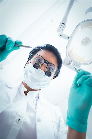 simsearch:400-07938824,k - Low angle view of female dentist in surgical mask holding dental tools Foto de stock - Super Valor sin royalties y Suscripción, Código: 400-07938835