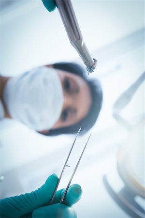 simsearch:400-07938964,k - Low angle view of female dentist in surgical mask holding dental tools Stockbilder - Microstock & Abonnement, Bildnummer: 400-07938830