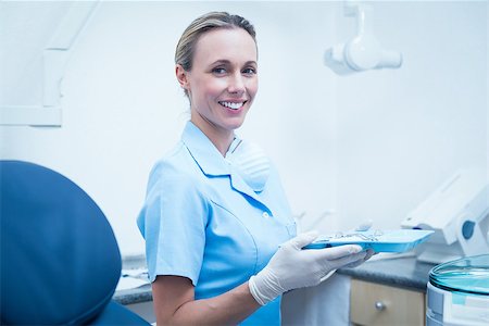 simsearch:400-07940798,k - Portrait of female dentist in blue scrubs holding tray of tools Foto de stock - Super Valor sin royalties y Suscripción, Código: 400-07938920