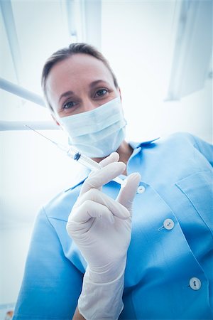 simsearch:400-07938947,k - Low angle portrait of female dentist in surgical mask holding injection Photographie de stock - Aubaine LD & Abonnement, Code: 400-07938944
