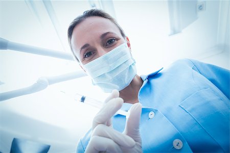 simsearch:400-07940798,k - Low angle portrait of female dentist in surgical mask holding injection Stock Photo - Budget Royalty-Free & Subscription, Code: 400-07938945