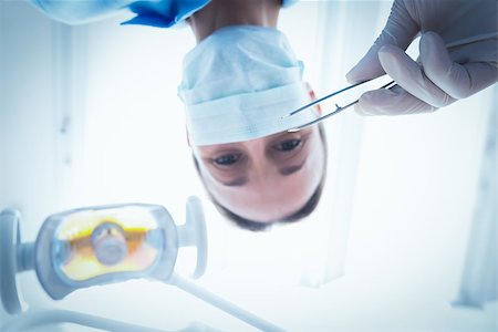 simsearch:400-07940798,k - Low angle portrait of female dentist in surgical mask holding dental tool Stock Photo - Budget Royalty-Free & Subscription, Code: 400-07938953