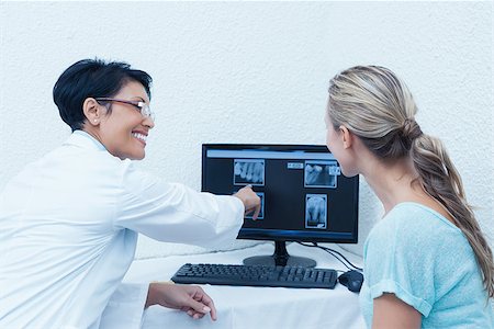 simsearch:400-07938824,k - Side view of female dentist showing woman her mouth x-ray on computer Foto de stock - Super Valor sin royalties y Suscripción, Código: 400-07939115