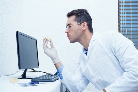 Male dentist holding mouth model besides computer Stockbilder - Microstock & Abonnement, Bildnummer: 400-07939174