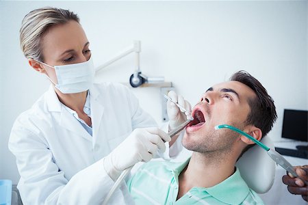 simsearch:400-07938947,k - Female dentist examining mans teeth in the dentists chair Photographie de stock - Aubaine LD & Abonnement, Code: 400-07939178