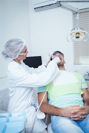 simsearch:6109-08389794,k - Female dentist examining mans teeth in the dentists chair Stockbilder - Microstock & Abonnement, Bildnummer: 400-07939189