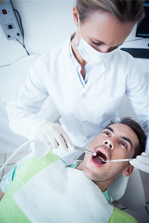 simsearch:6109-08389794,k - Female dentist examining mans teeth in the dentists chair Stockbilder - Microstock & Abonnement, Bildnummer: 400-07939197
