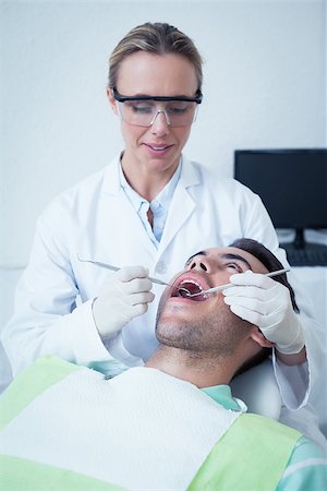 simsearch:6109-08389794,k - Female dentist examining mans teeth in the dentists chair Stockbilder - Microstock & Abonnement, Bildnummer: 400-07939190