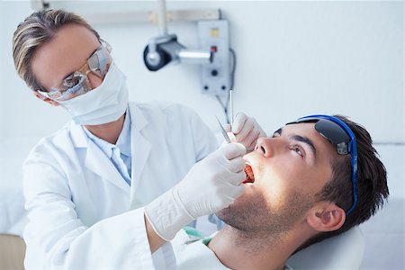 simsearch:6109-08389794,k - Female dentist examining mans teeth in the dentists chair Stockbilder - Microstock & Abonnement, Bildnummer: 400-07939204